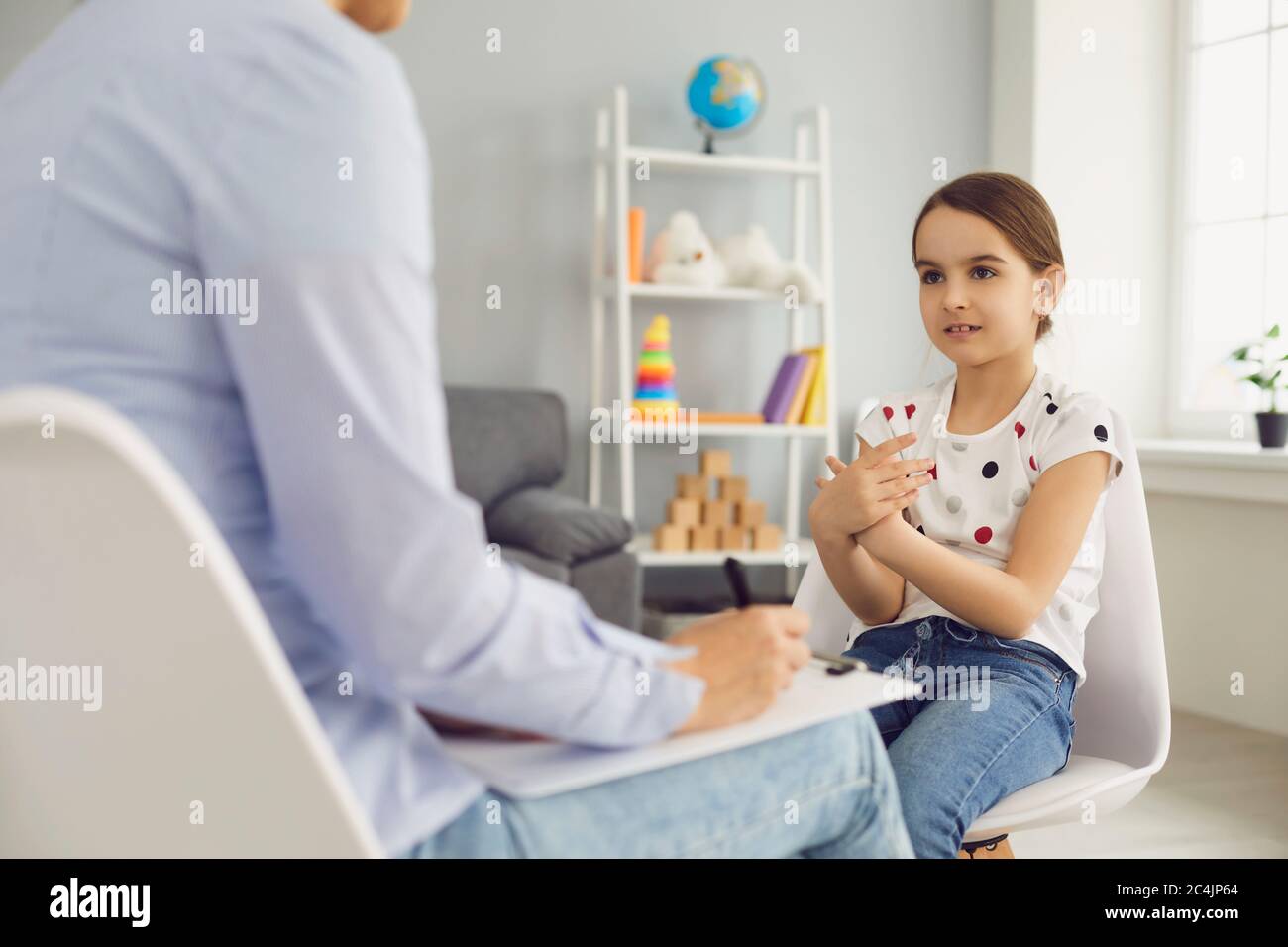 Lovely little girl talking to child psychotherapist at medical office. Mental health problem treatment Stock Photo