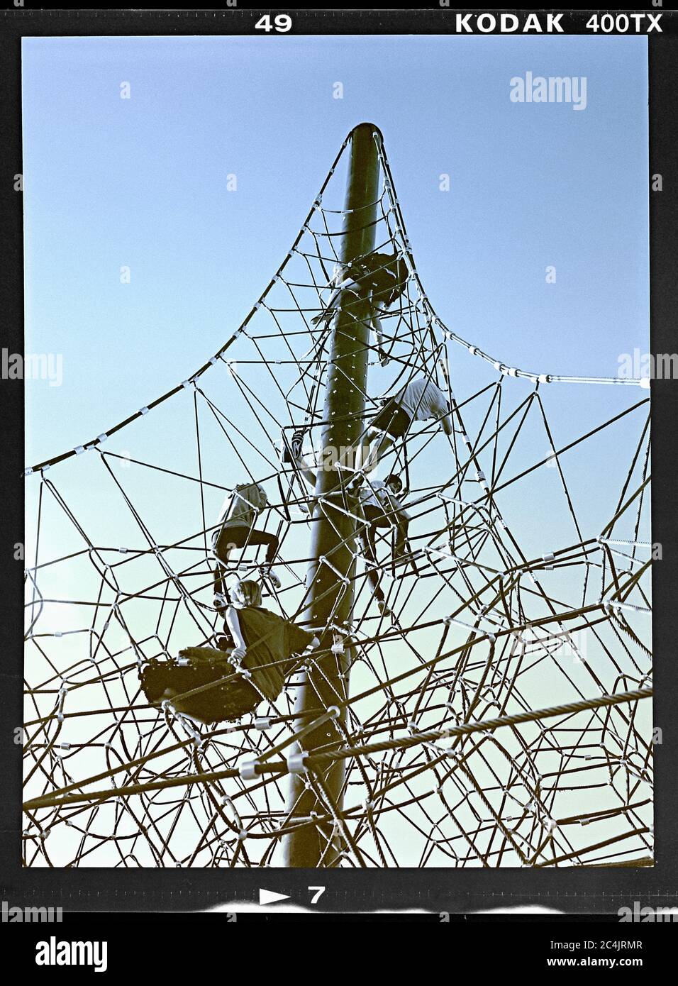 Kids climbing a tower made of rope on a park playground. Riverview Park, Mesa, Arizona.  March 21, 2020. Image colorized from B&W  6x4.5 cm negative. Stock Photo