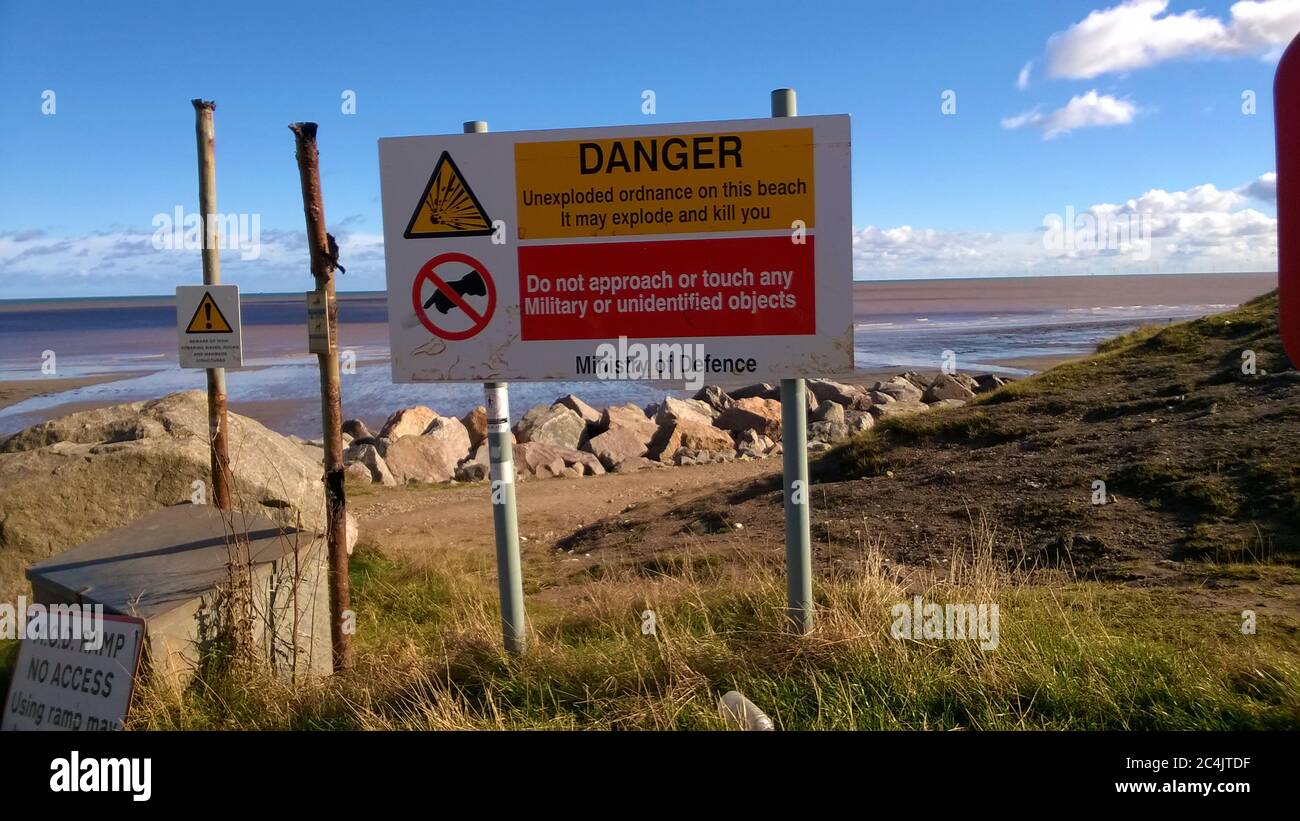 2017 warning sign of unexploded ordinances bombs,grenades,shells,explosives) on the beach near Hornsea, Yorkshire, UK . (During the Second World War the town and beach was heavily fortified against invasion.) Stock Photo