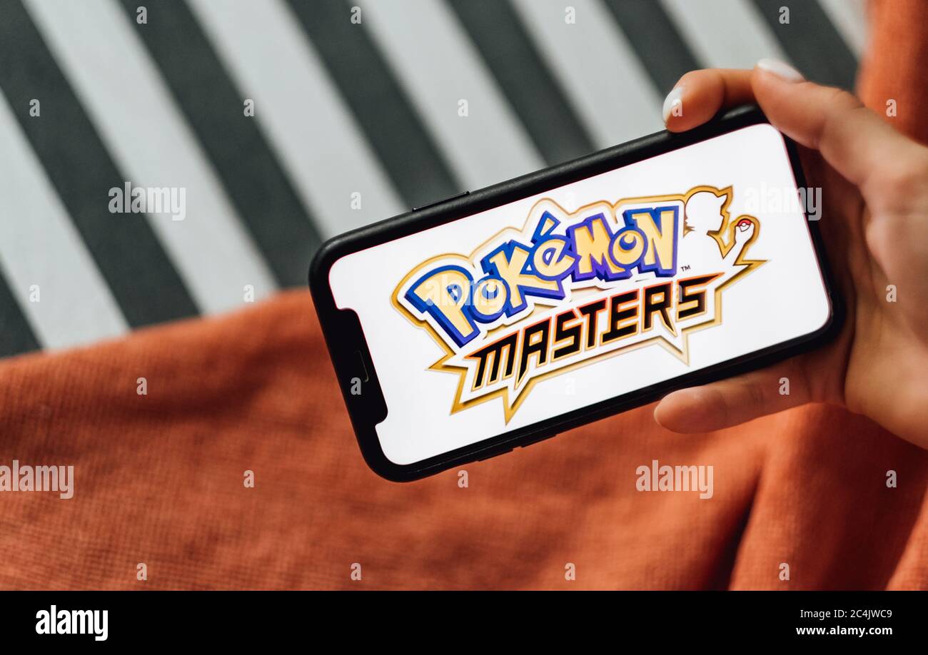Hands holding iPhone with Pokemon masters on the screen. Stock Photo