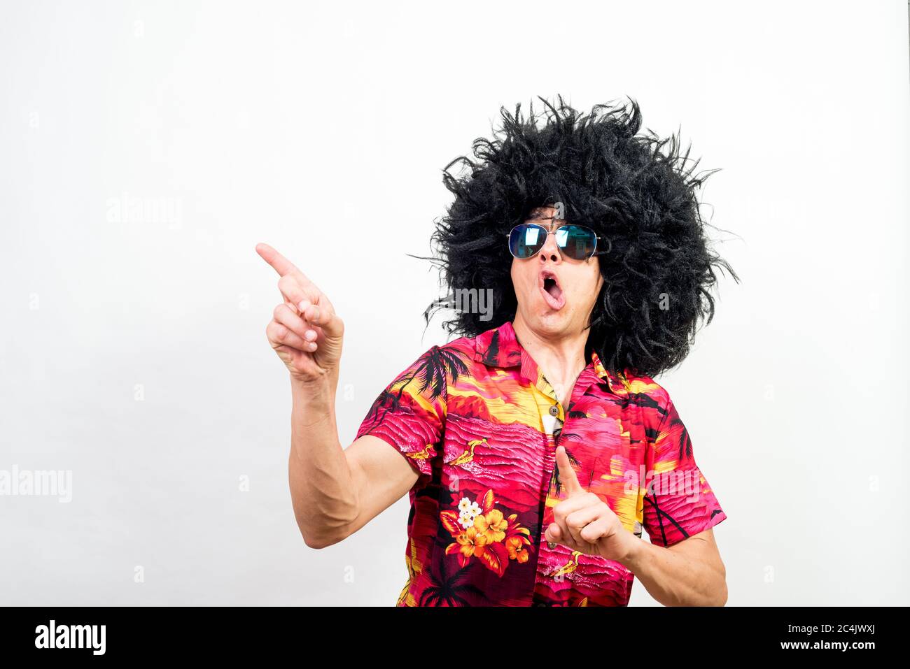 Man with afro wig, sunglasses and hawaiian shirt, very crazy. Mid shot. White background. Stock Photo