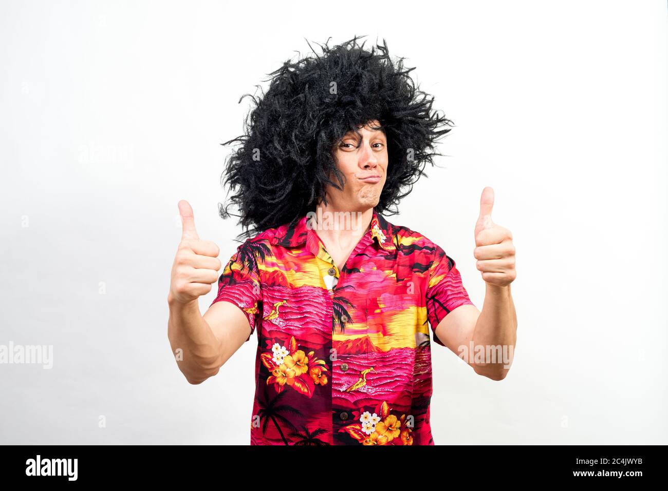 Man in afro wig and hawaiian shirt, very satisfied, with thumb up. Mid shot. White background. Stock Photo