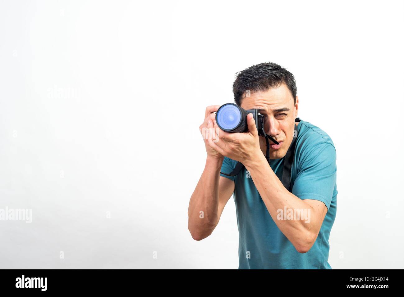 Man with photo camera photographing something very concentrated, looking straight ahead. Mid shot. White background. Stock Photo