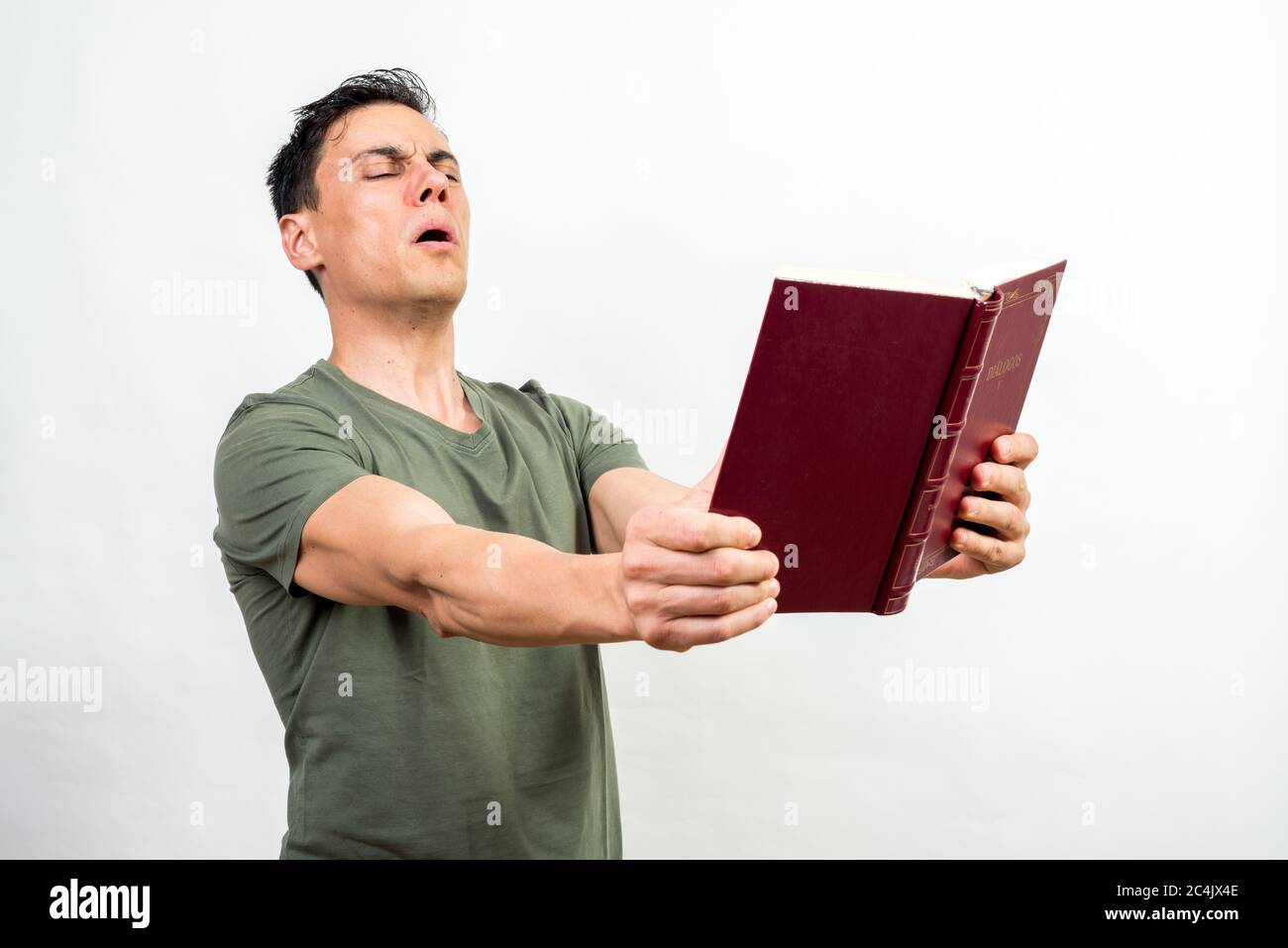 Man spreading a book as far as he can with his arms because he can't see well. Stock Photo