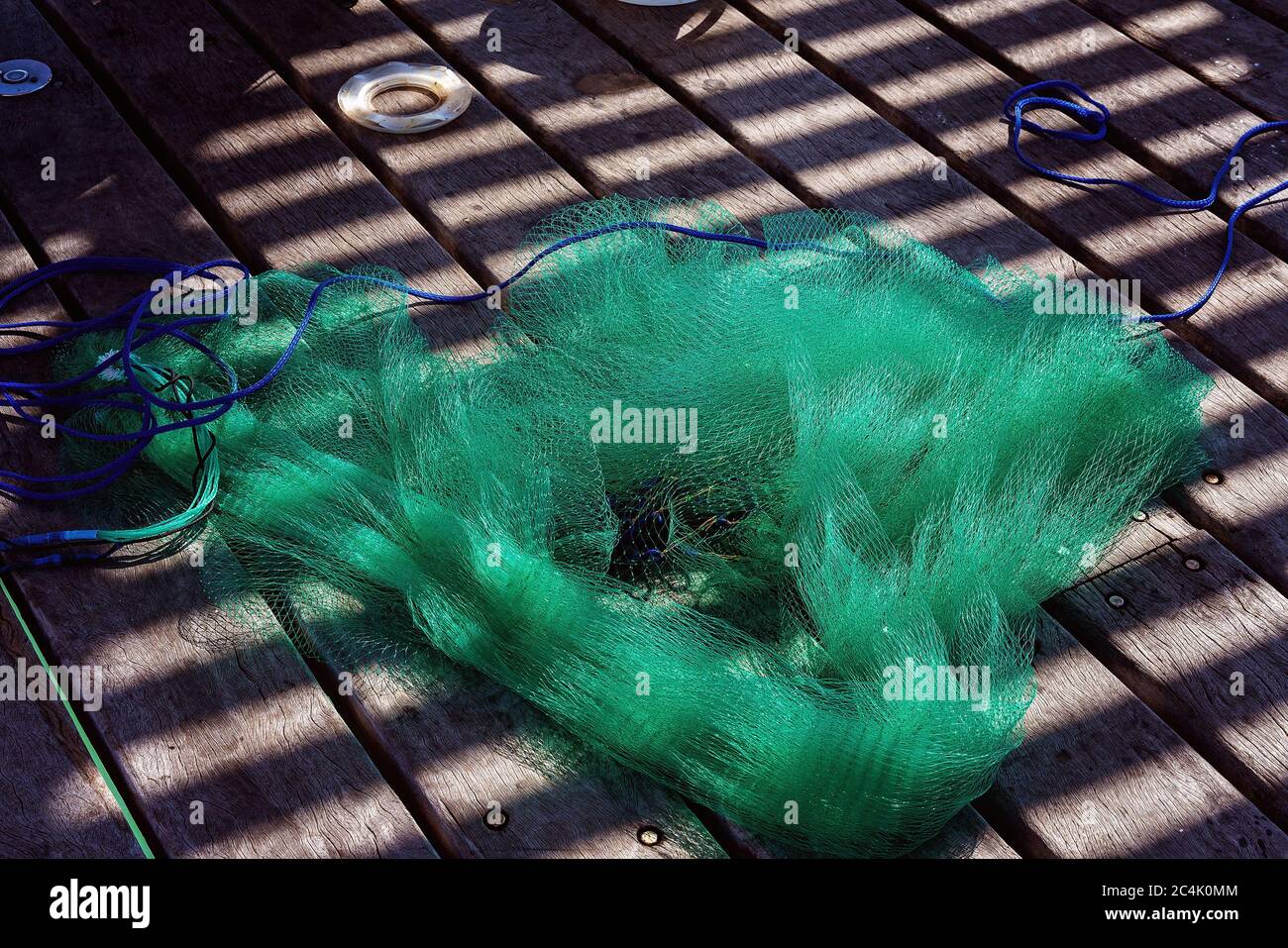 A green fishing net lying tangled on a timber deck Stock Photo Alamy