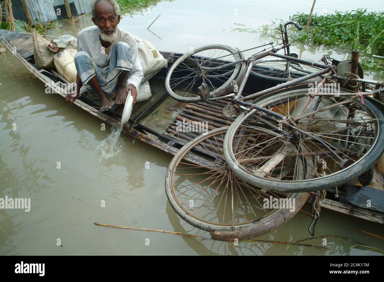 An old man bailing water from a boat in the flood affected area. Gaibandha, Bangladesh. July 21, 2004. Stock Photo