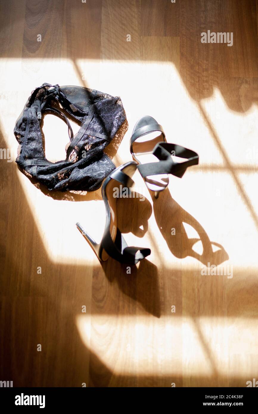 Black Lingerie and Black High Heels lying on the floor in the sunshine coming in through the window Stock Photo