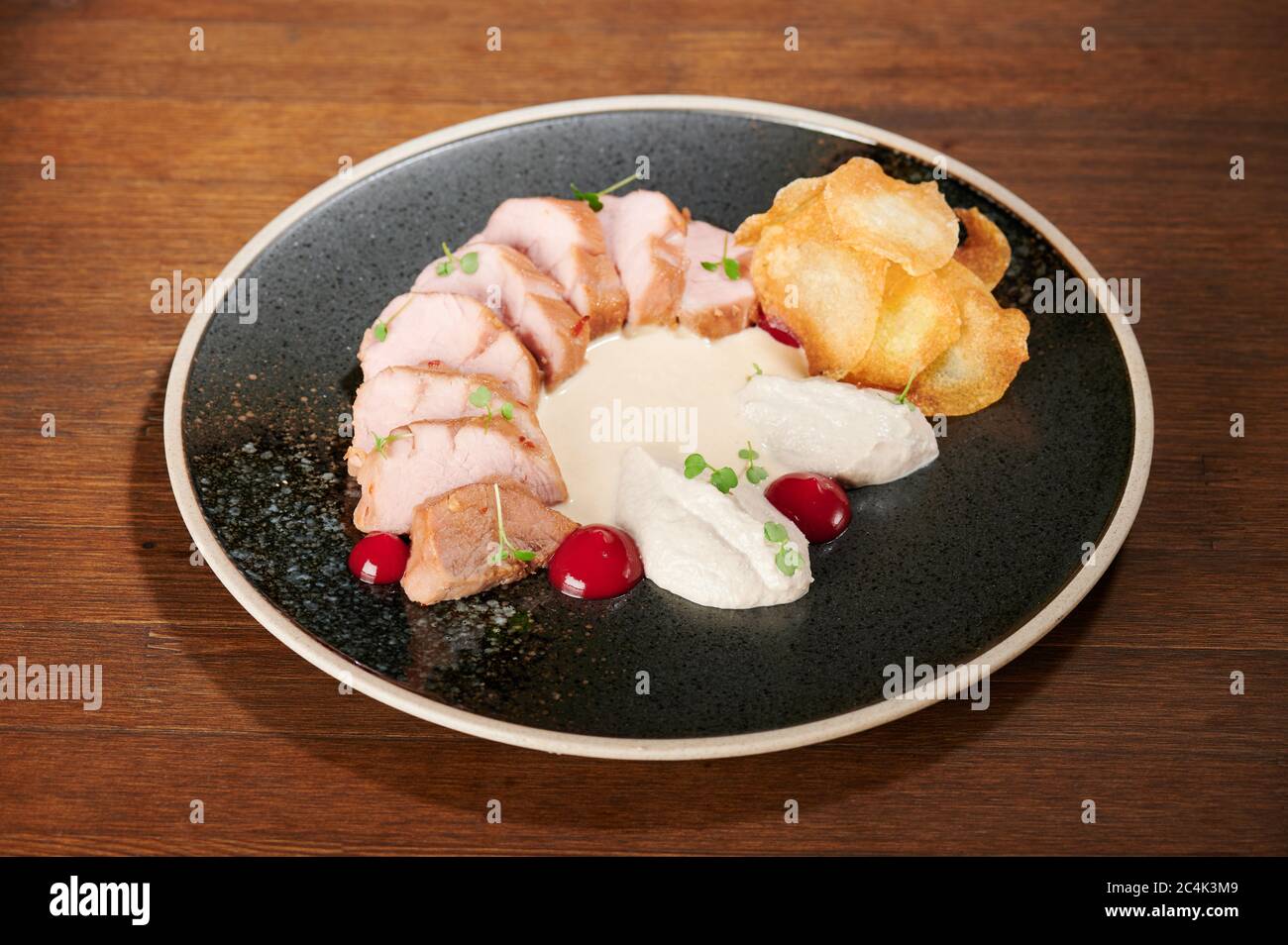 Fresh sliced pork meal on black plate close up view Stock Photo