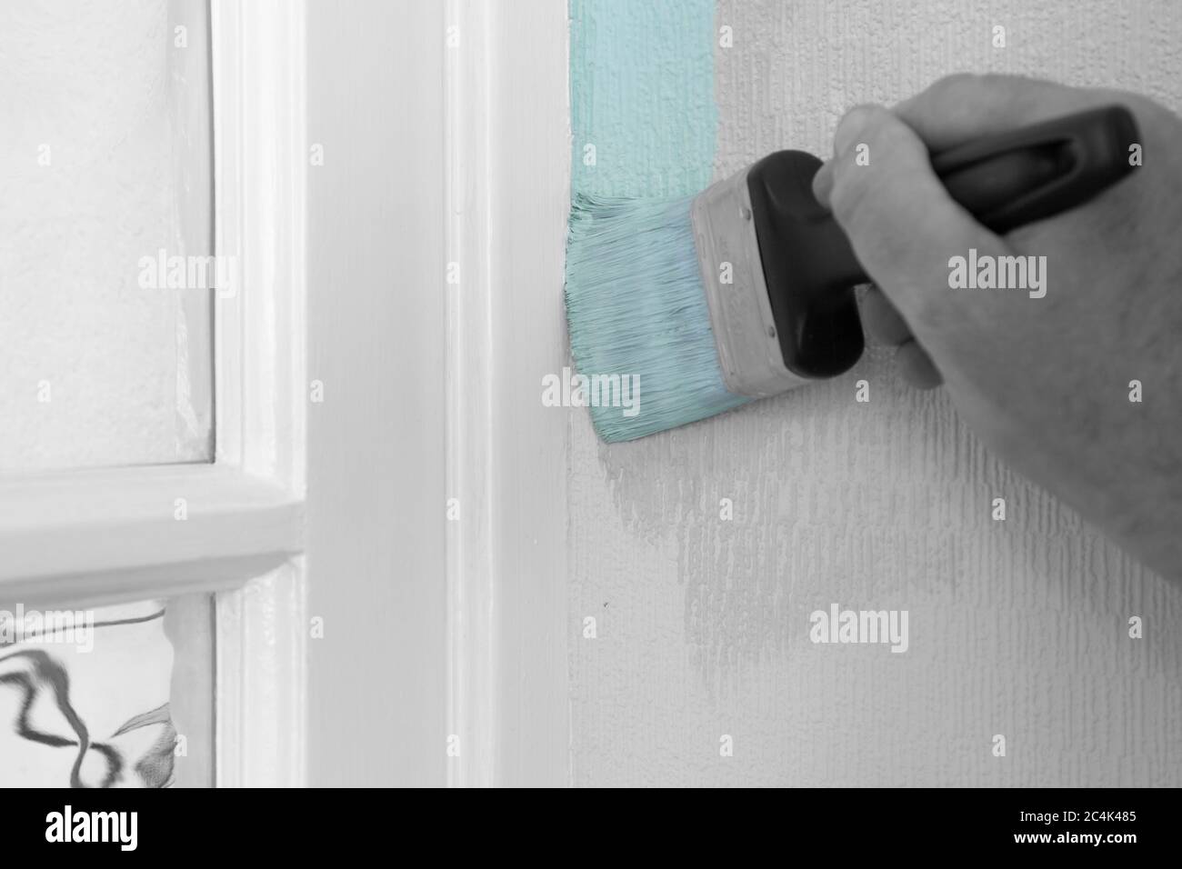 Man painting wall with mint green paint on textured wallpaper, cutting