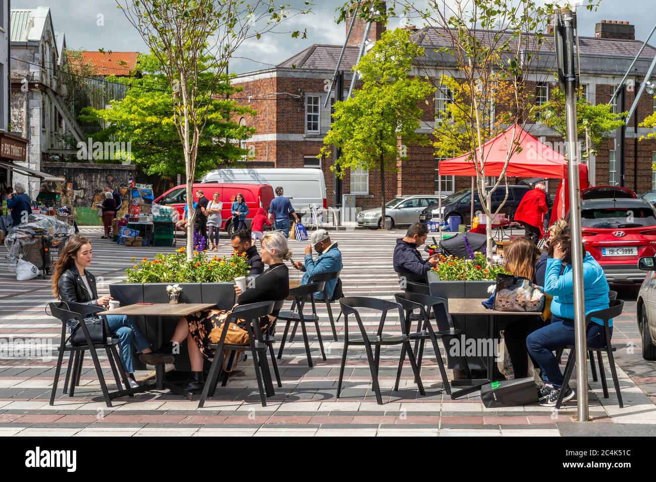People relaxing at chairs and tables outside a café in Coal Quay, Cork City, Ireland Stock Photo