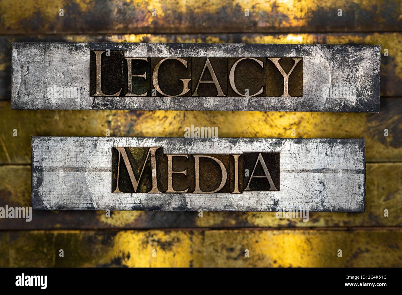 Legacy Media text formed with real authentic typeset letters on vintage textured silver grunge copper and gold background Stock Photo