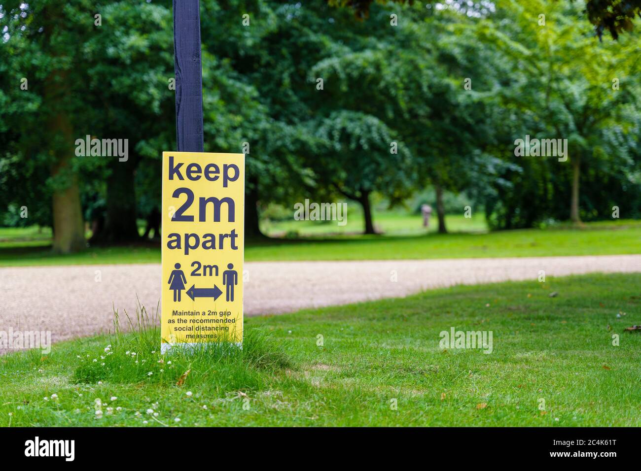 Keep 2 meters apart sign to the left in a park Stock Photo