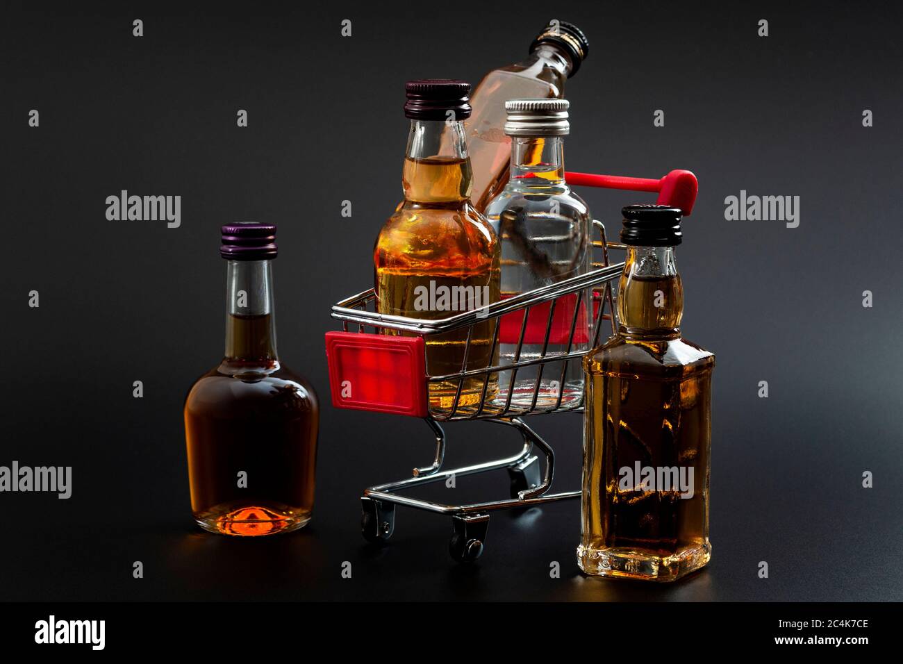 Buy booze, shopping the liqueur aisle and purchase of alcoholic beverages concept theme with mini bottles of alcohol in a small supermarket cart isola Stock Photo