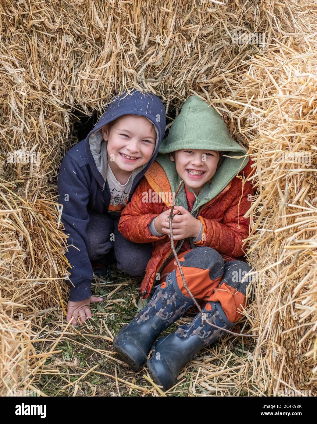 two kids playing in a haystack Stock Photo