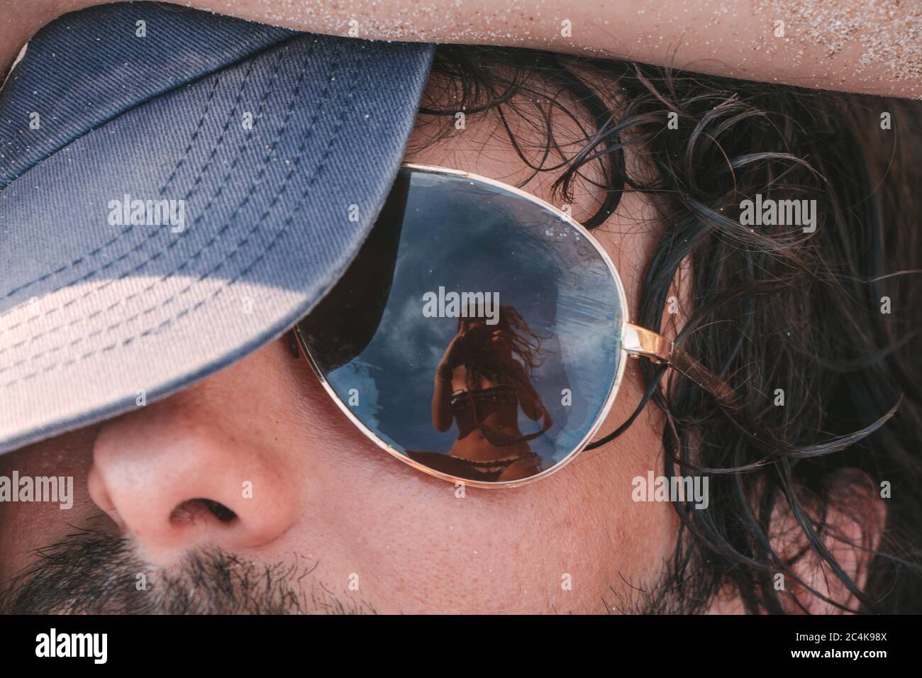 A woman's reflection in a man's sunglasses, as she takes a photo Stock Photo