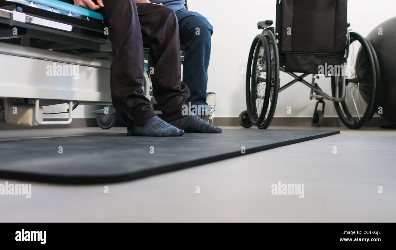 Physiotherapist exercising with disabled person using wheelchair on a therapy table Stock Photo