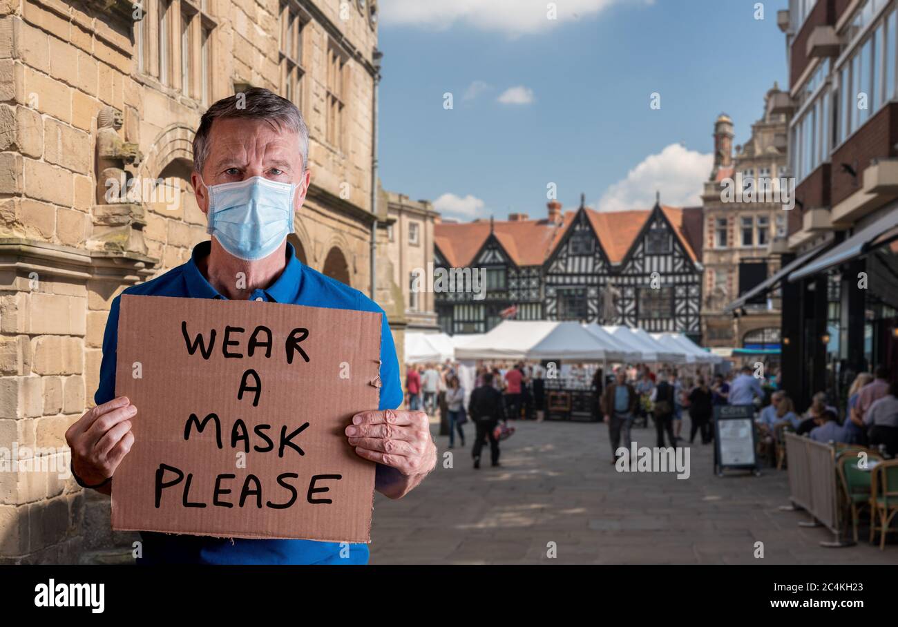 Senior caucasian man holding a blank cardboard sign saying wear a mask. He is isolated against a white background Stock Photo