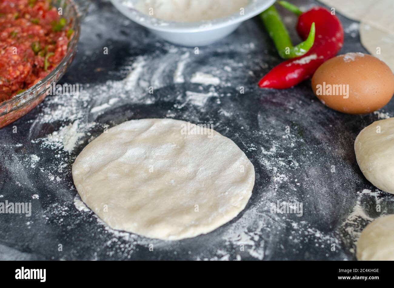 Turkish lahmacun dough and minced meat,egg,pepper on the table , top view.Concept of home cooking, baking at home. Stock Photo