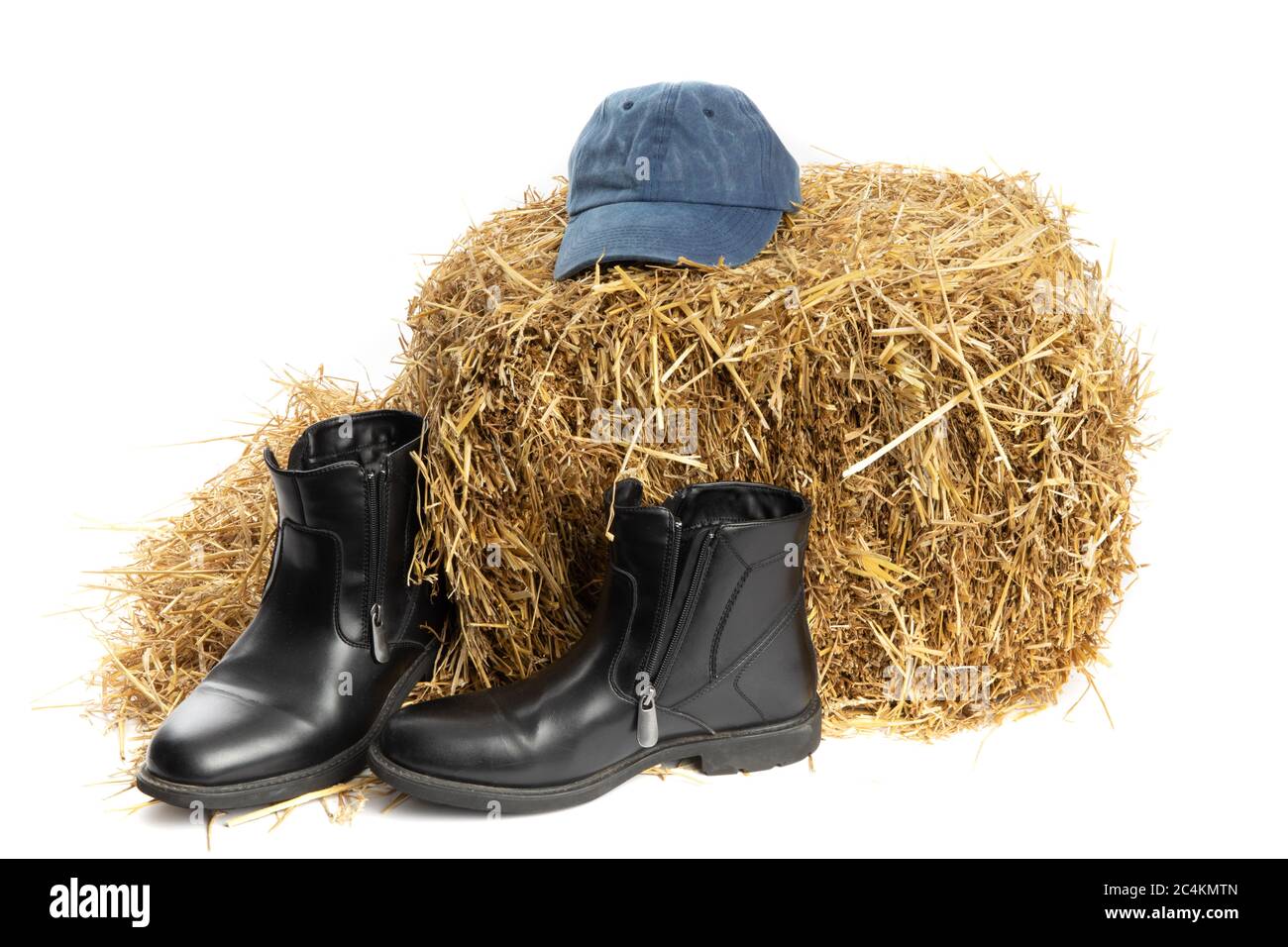 farm fashion, blue denim hat and black leather boots on a straw bale in a barn isolated on white Stock Photo