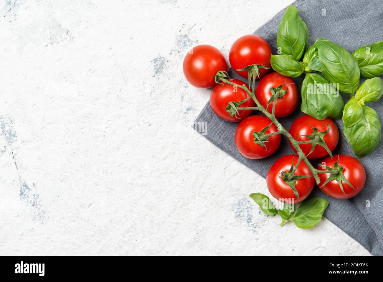 Fresh red ripe cherry tomatoes with green basil leaves, top view with ...