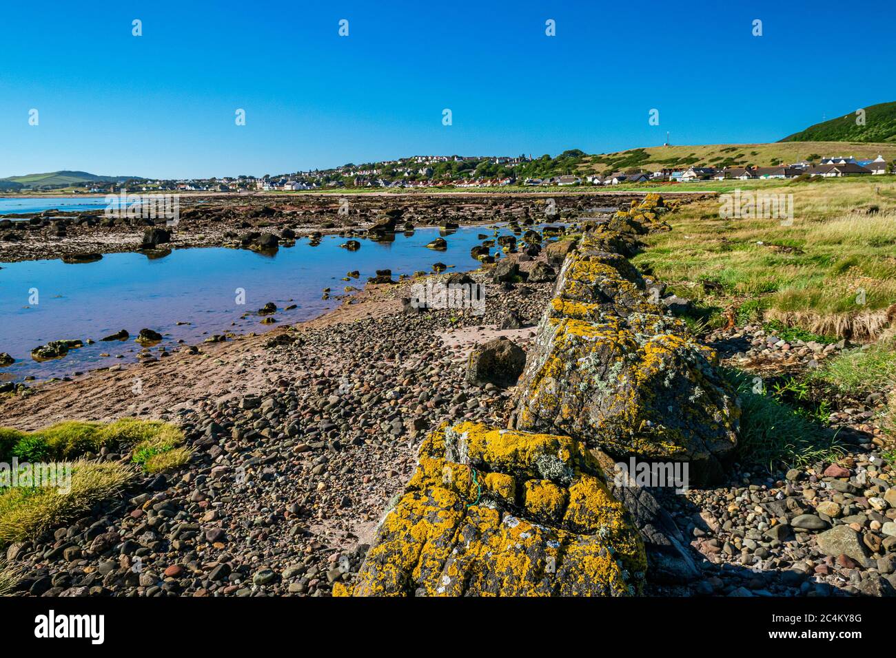 Rocky beach near the Scottish village of Seamill in Firth of Clyde on a sunny summer afternoon. Scottish coastal landscape. Stock Photo