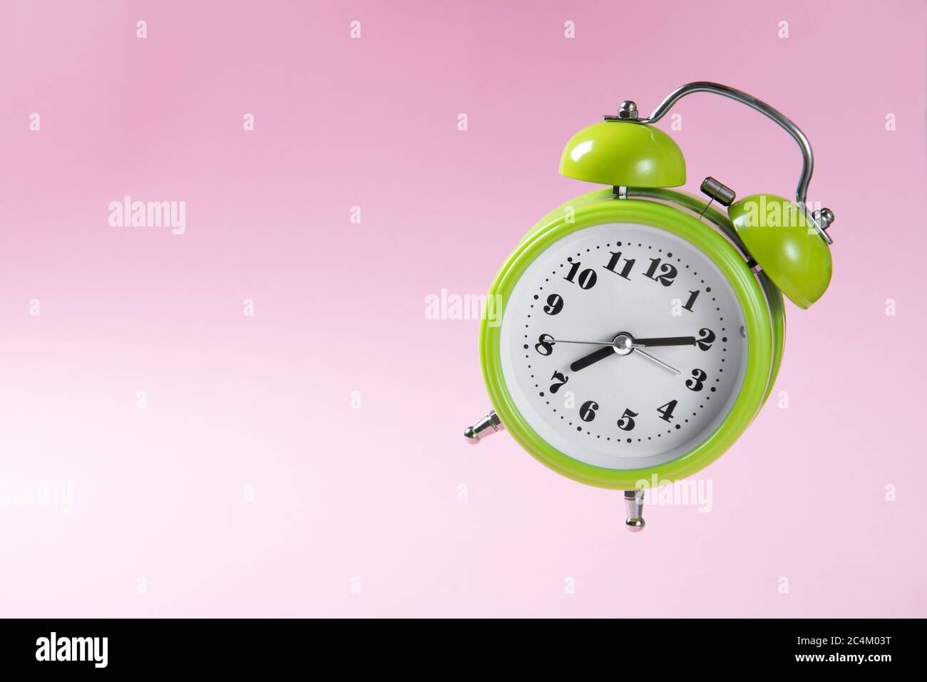 Green retro alarm clock with two bells showing ten minutes past seven