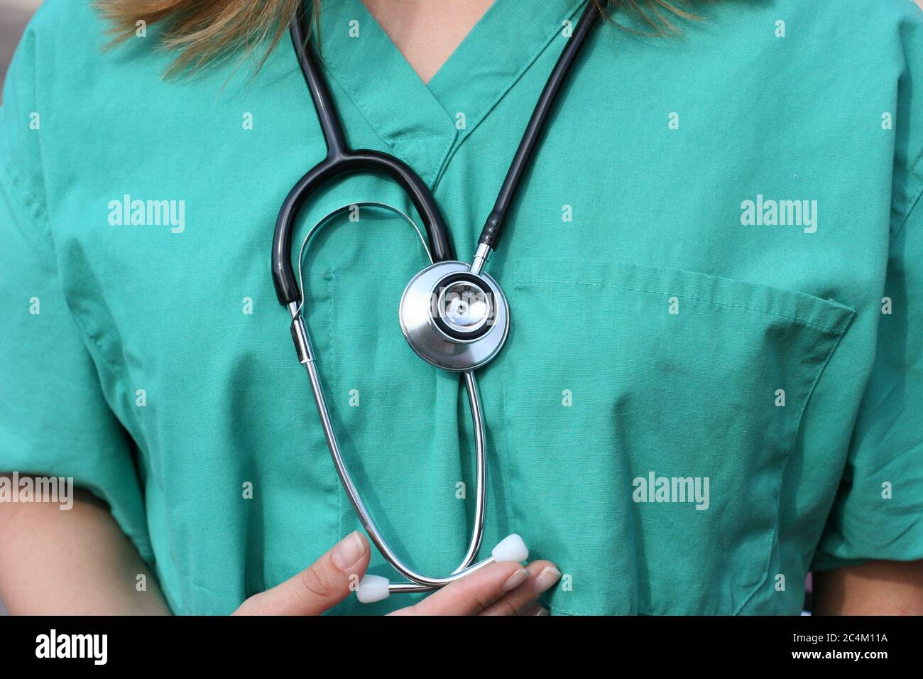 Medical nurse on checkup with green scrubs & medical stethoscope for heart health. Stock Photo