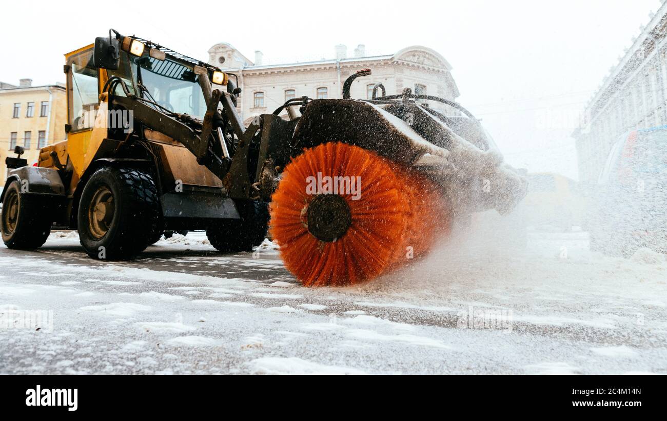 Snowplow truck vehicle removing snow after blizzard and snowstorm in motion. Urgent city street cleaning at daylight. Snowfall at European city. Winte Stock Photo