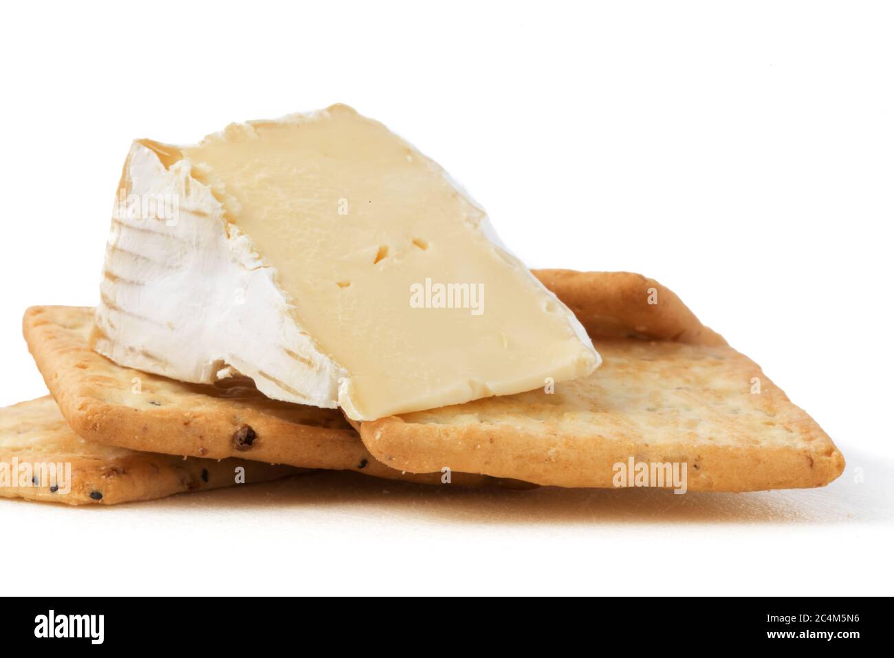 extreme closeup of a wedge of brie cheese with multigrain crackers