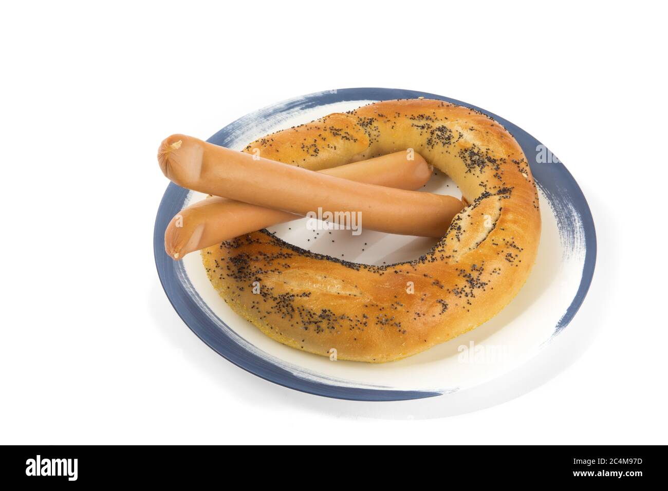 a large poppy seed pretzel bagel and two wiener sausages on a blue plate isolated on white Stock Photo