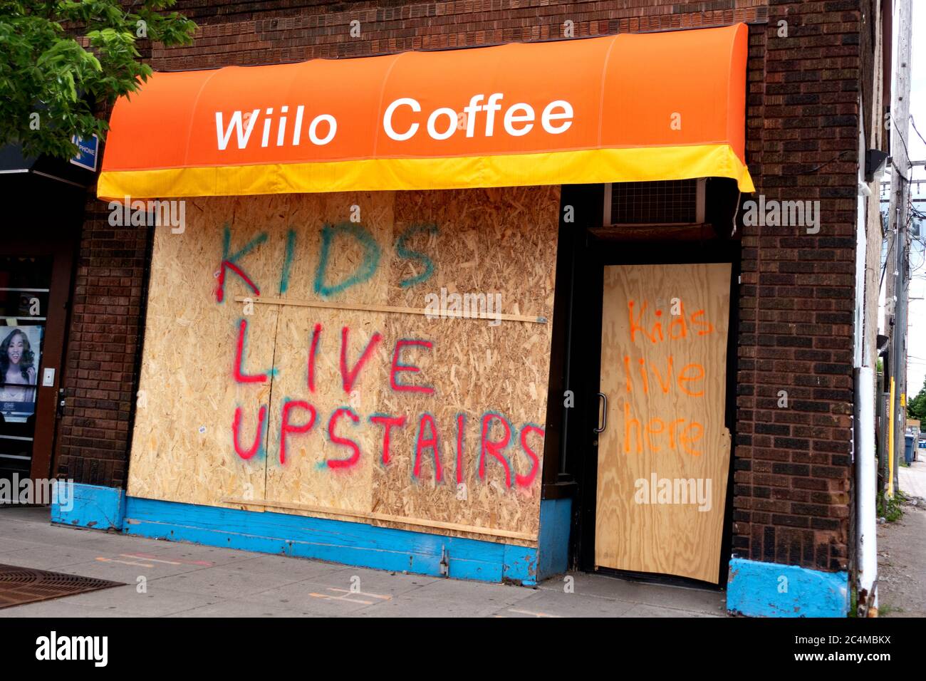 Kids Live upstairs on Wiilo Coffee Shop boarded window after turmoil from George Floyd death. Minneapolis Minnesota MN USA Stock Photo