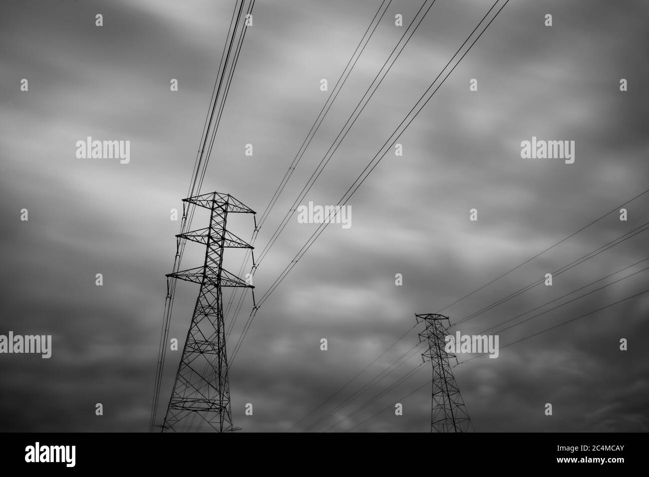 Dramatic Close-up transmission towers (power tower, electricity pylon, steel lattice tower) cloud dark sky in New Zealand. Stock Photo