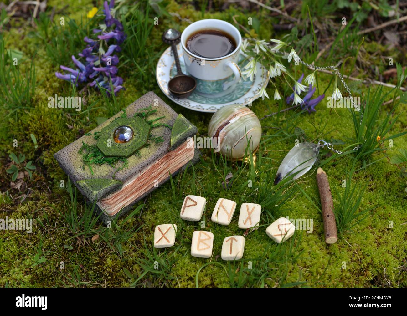 Still life with crafted witch diary, tea set, runes and crystals in the garden. Esoteric, gothic and occult background with magic objects, mystic and Stock Photo
