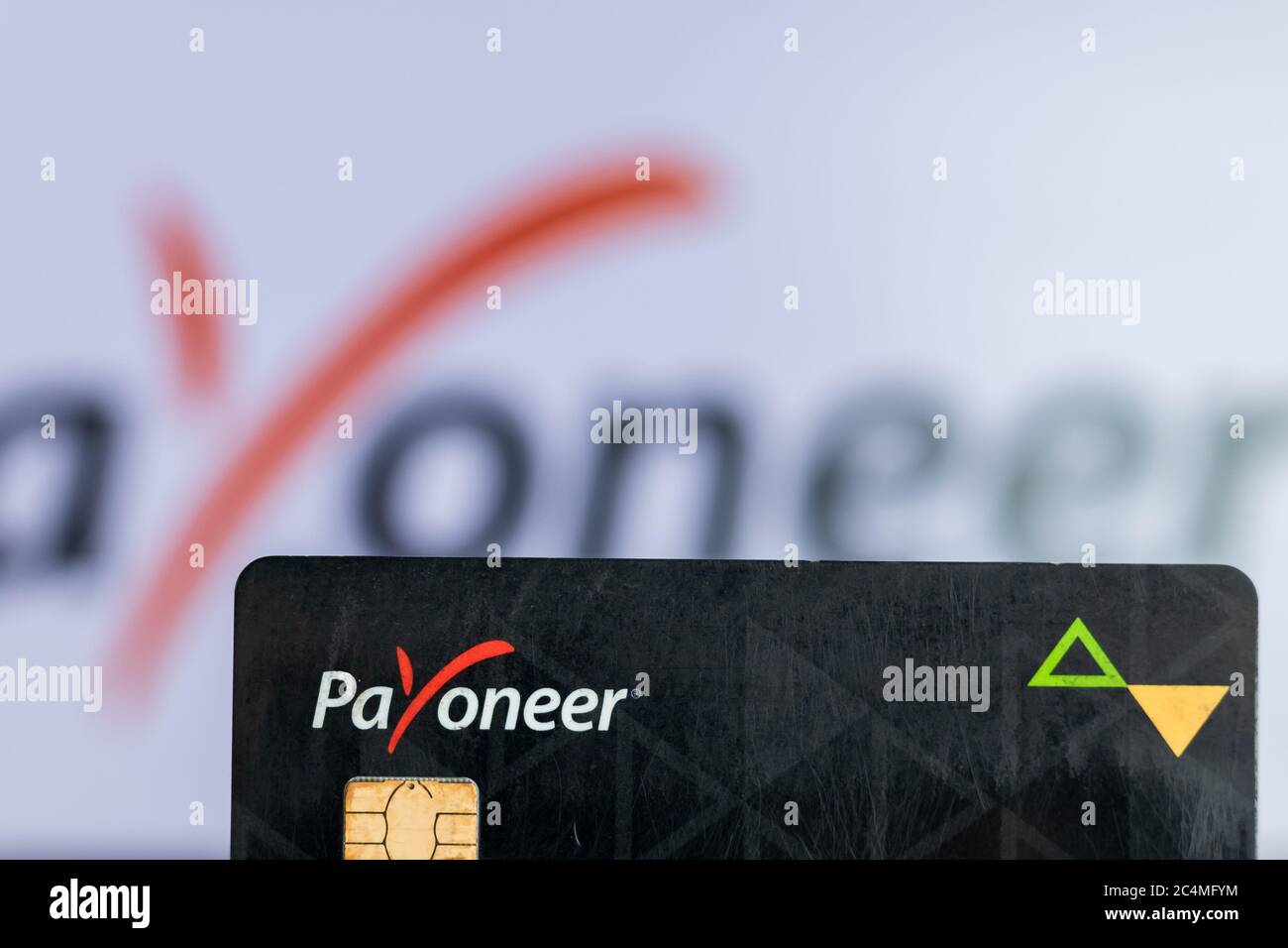 Bhairahawa, Nepal - June 27 2020: Man holds Payoneer Prepaid MasterCard against laptop computer. Payoneer funds were recently put on hold due to insol Stock Photo