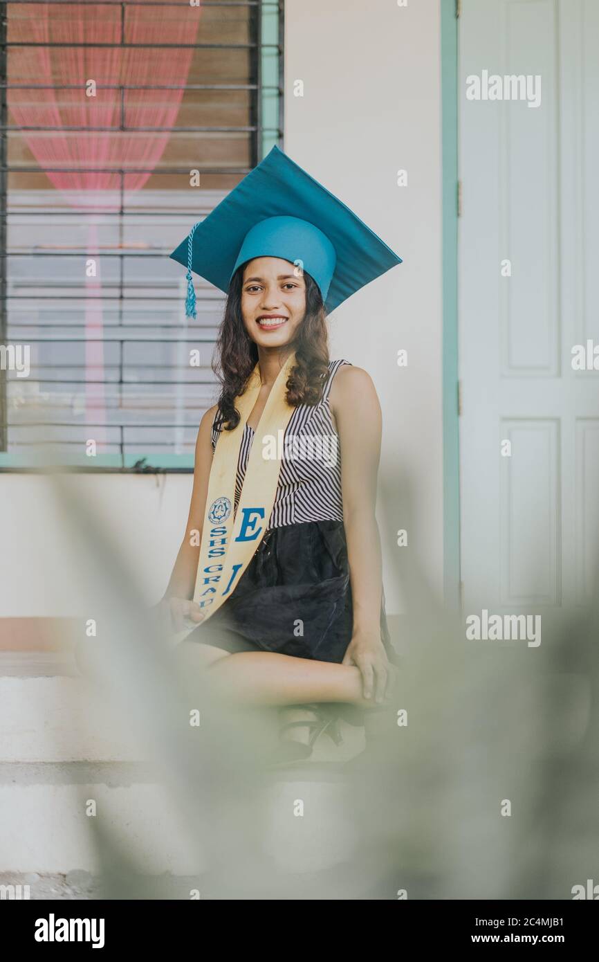 Portrait of a Filipino Woman wearing her Graduation cap, gown and Sash