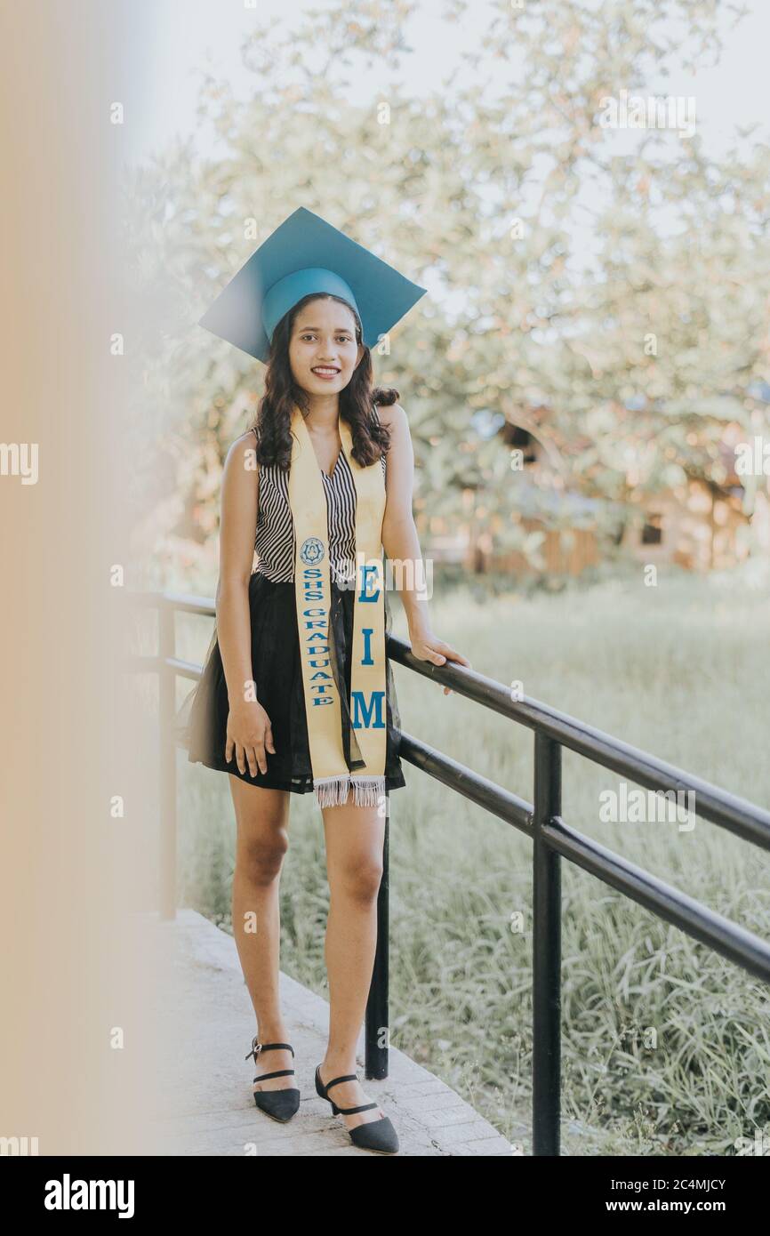 Portrait of a Filipino Woman wearing her Graduation cap, gown and Sash