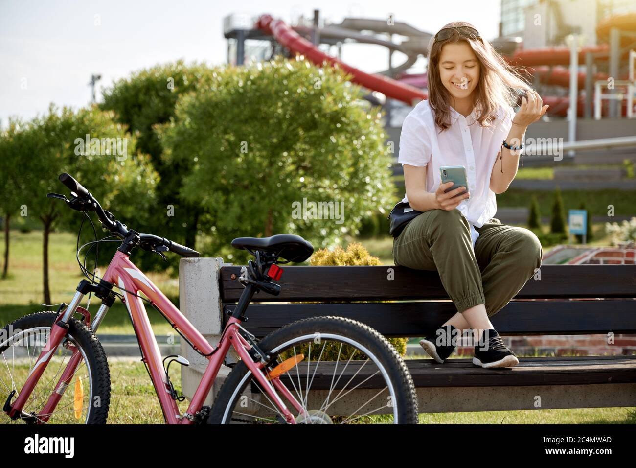 Urban biking teenage girl with phone, bike in city.  Active lifestyle. Stock Photo