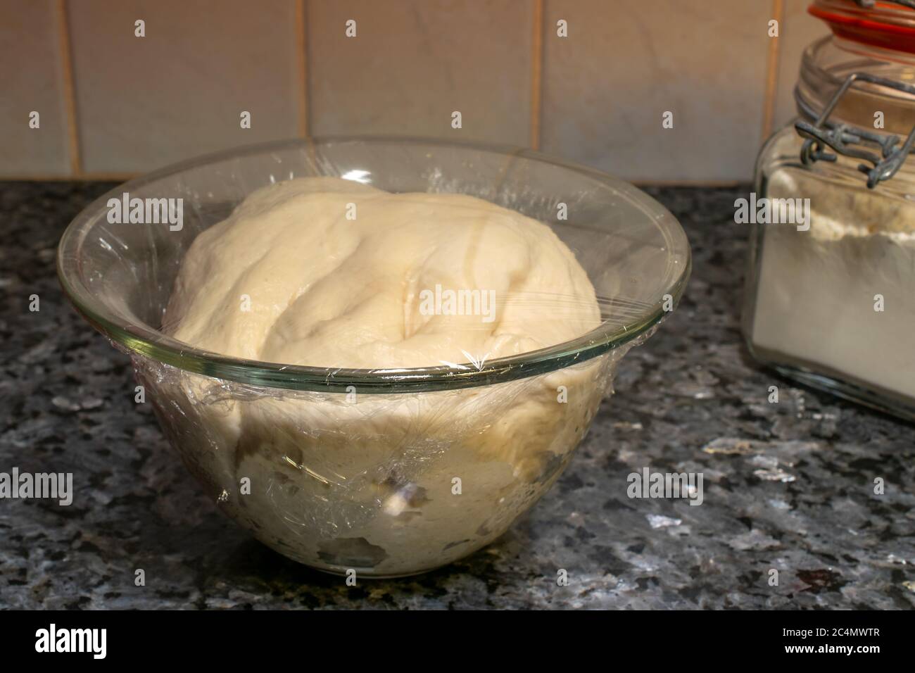 Closeup of dough in a bowl wrapped in a cling film on the table under the lights Stock Photo Alamy