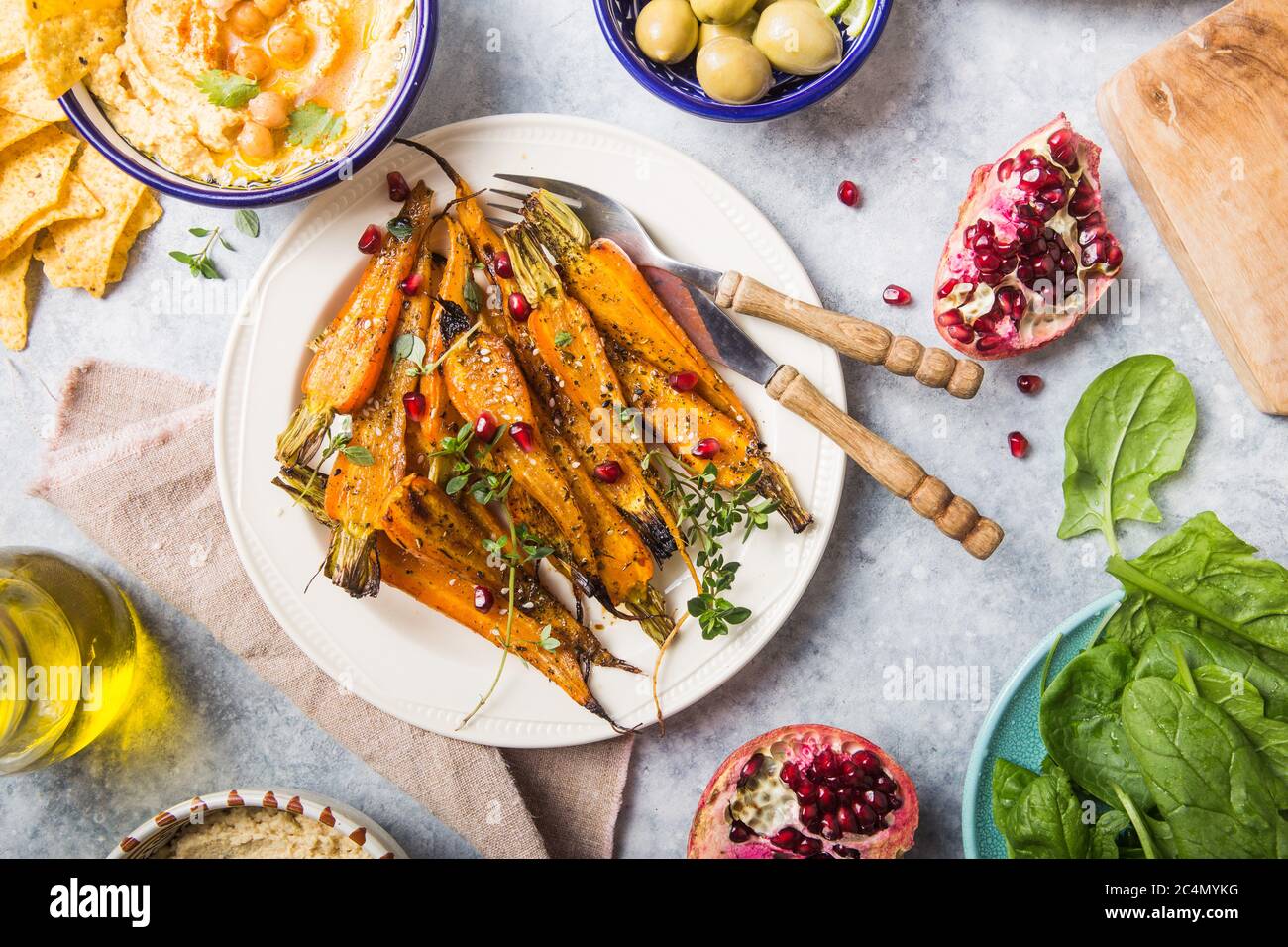 Variety of healthy vegan snacks, gourmet dips. Hummus, roasted carrots, rice with tempeh in ceramic bowls viewed from above, plant based food Stock Photo