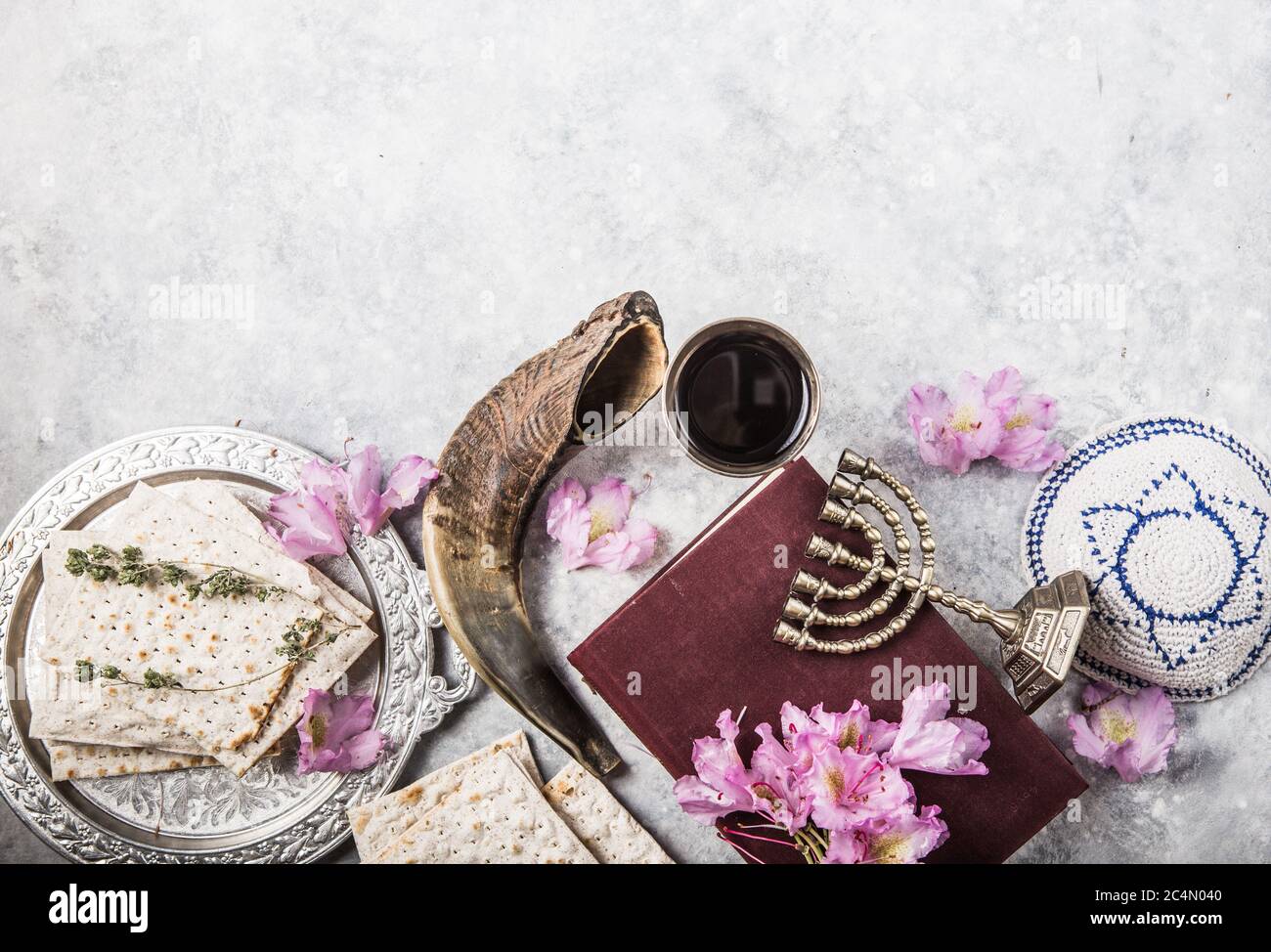 Metal plate with matzah or matza, Kiddush Cup, Shofar horn  on a light  background presented as a Passover seder feast or meal with copy space. Jewish Stock Photo