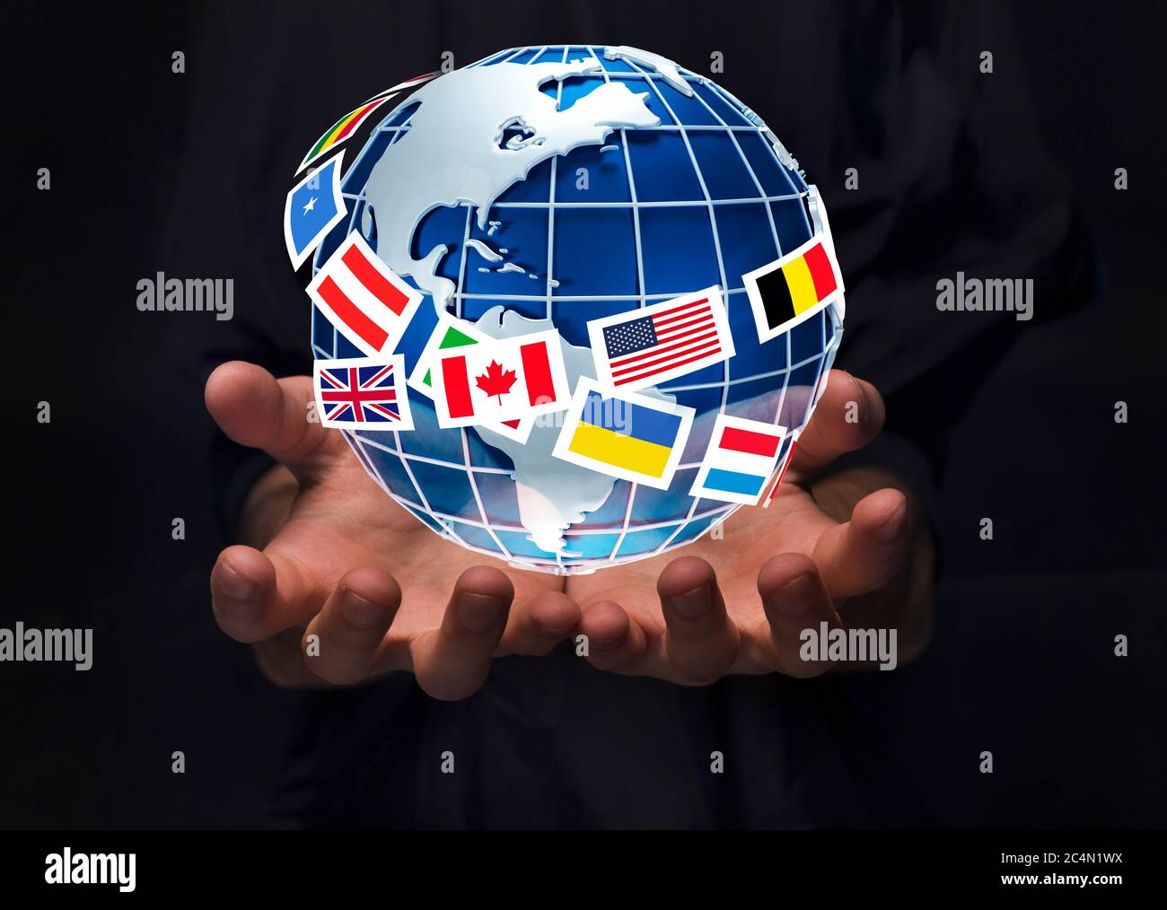 Closeup of man holding planet Earth surrounded by international flags on black background, collage Stock Photo