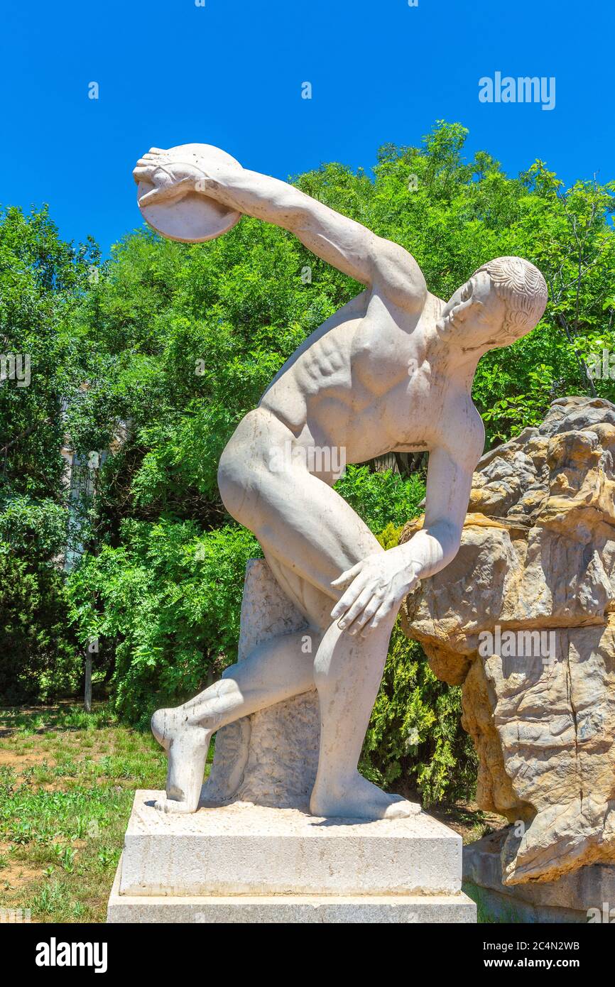 Outdoor blue sky, green tree and discus thrower sculpture, Greek sculptor Myron made around 450 BC Stock Photo