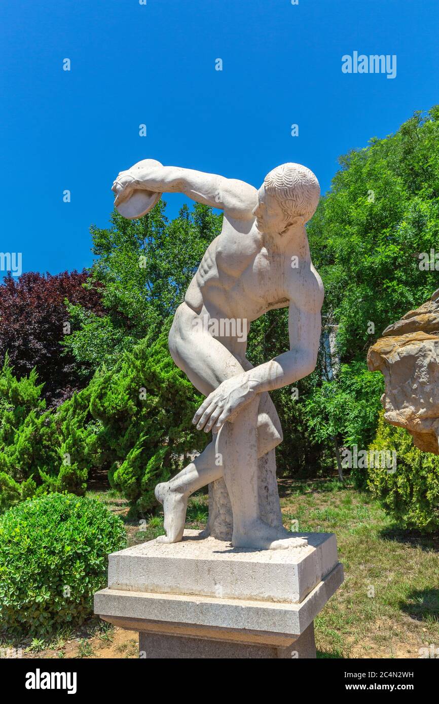 Outdoor blue sky, green tree and discus thrower sculpture, Greek sculptor Myron made around 450 BC Stock Photo