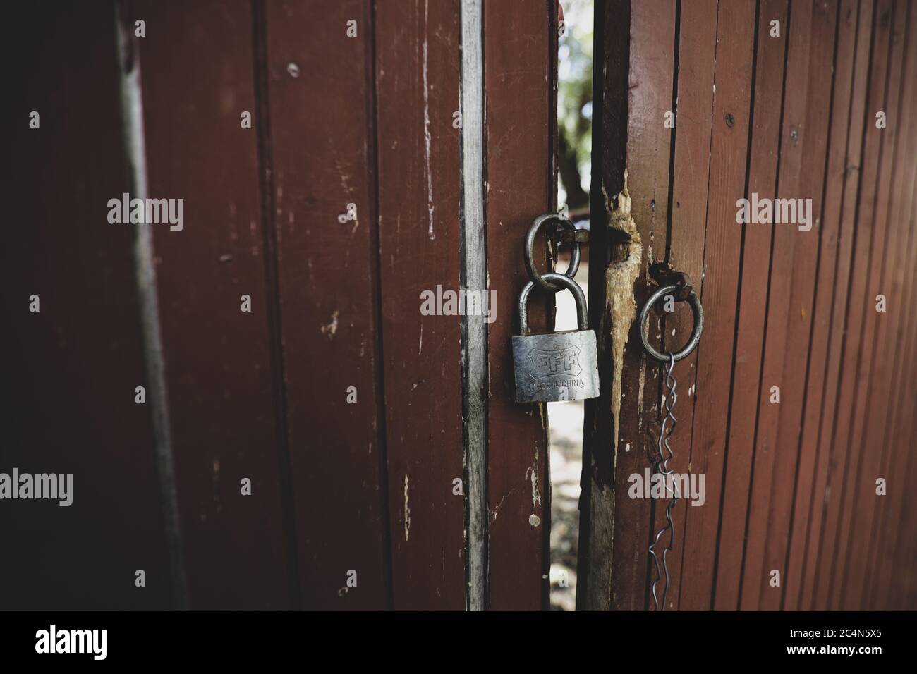 Metal padlock on an old and worn out wooden gate. Stock Photo