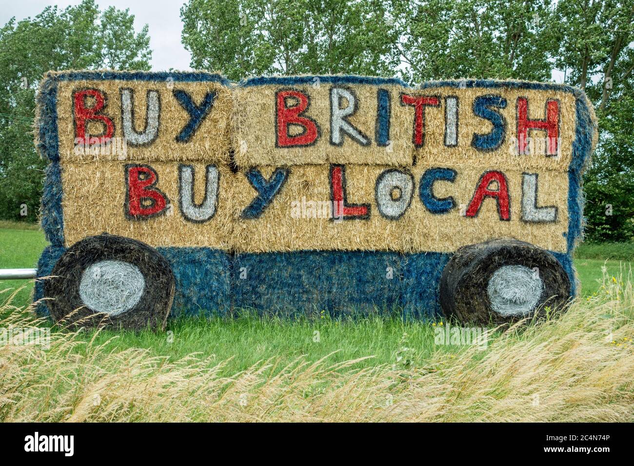 Buy British buy local slogan painted on side of straw bales, Cambridgeshire, England Stock Photo