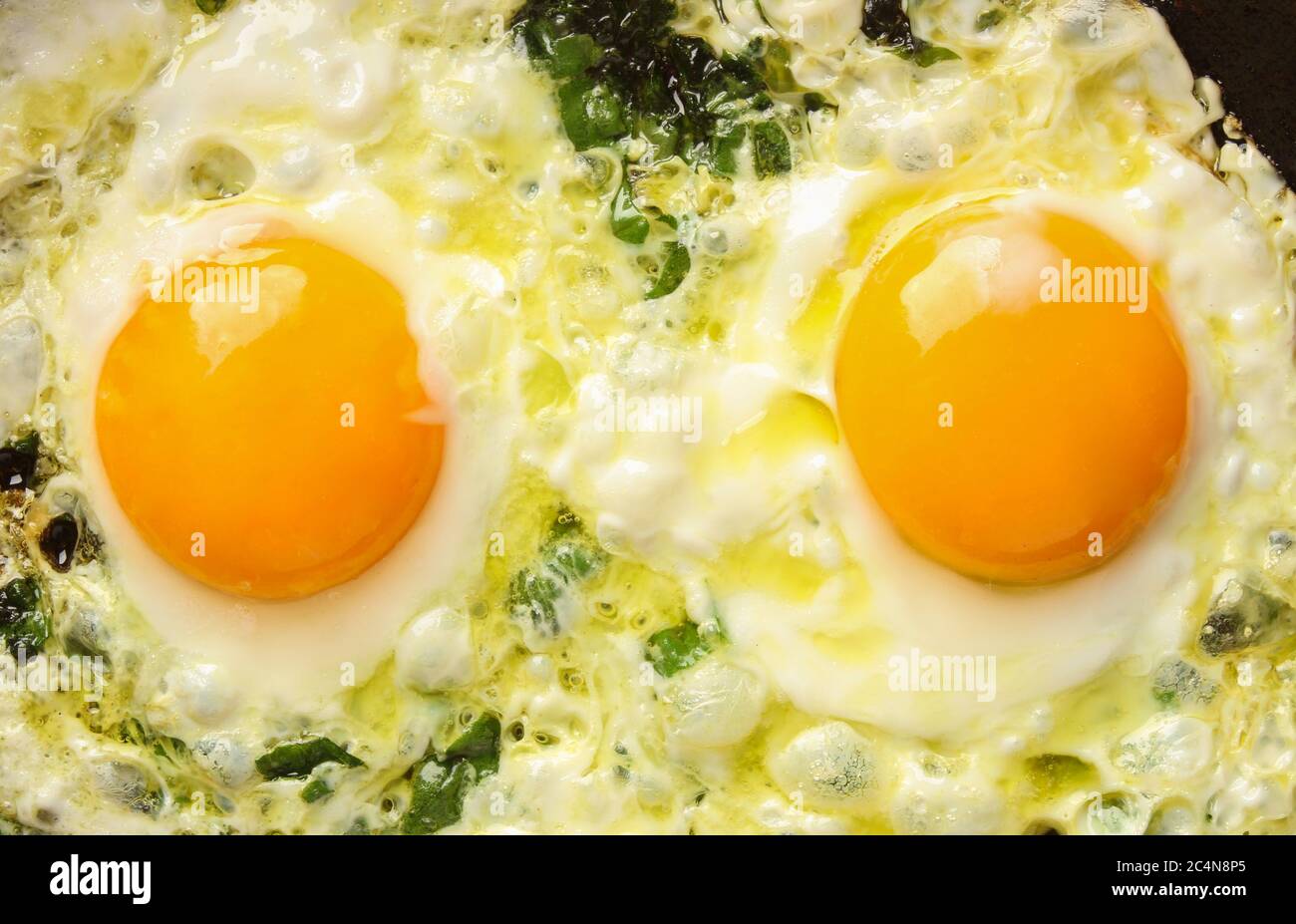 Fried eggs with spinach in a pan. View from above Stock Photo