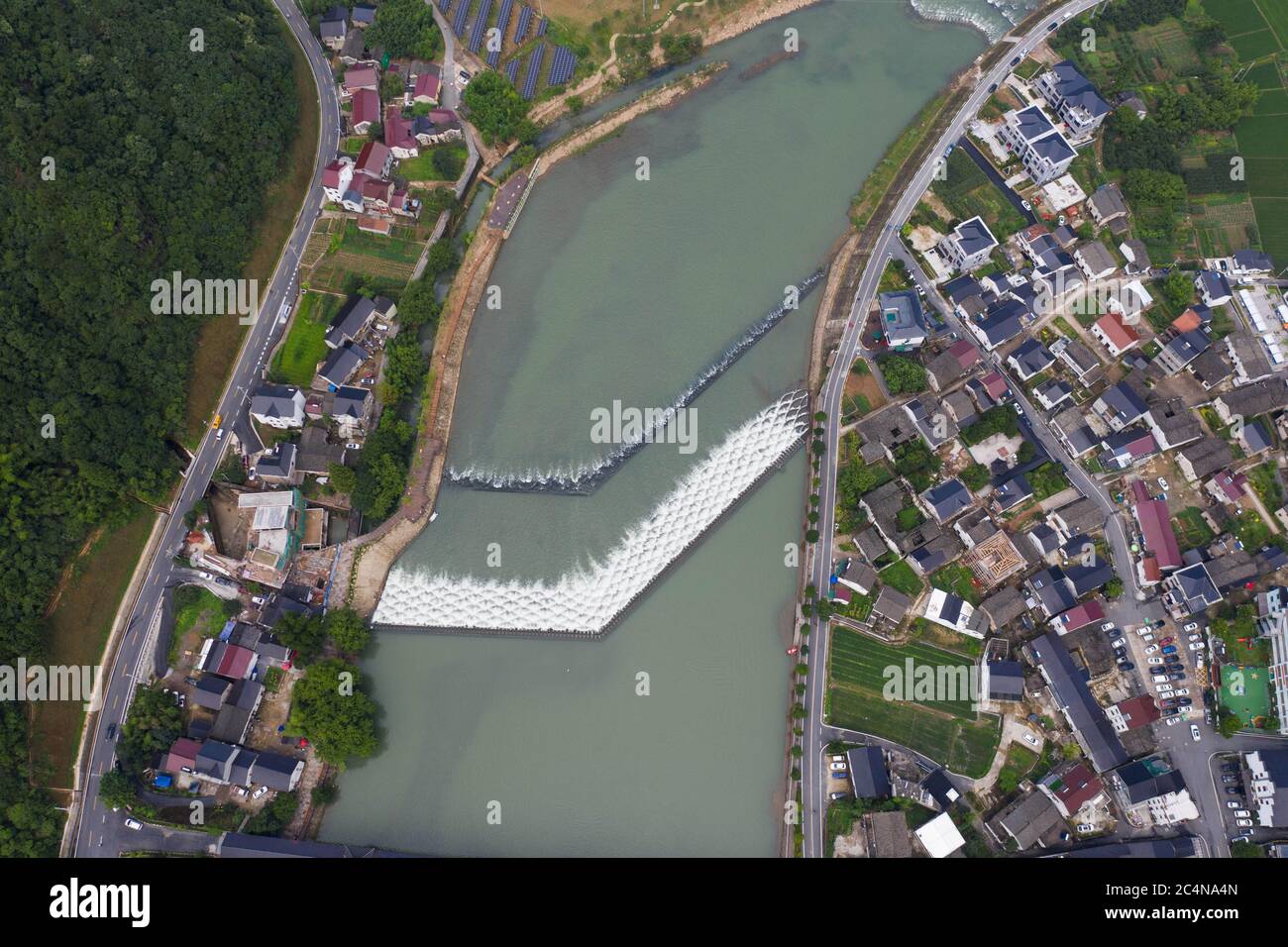 Hangzhou. 28th June, 2020. Aerial photo taken on June 28, 2020 shows water flowing through a dam with scale-shaped geometric structures on the Huyuan River in Huyuan Township of Fuyang District, Hangzhou, east China's Zhejiang Province. Township-level governments in Fuyang District have worked in collaboration to maximize the Huyuan River's ecological resources and promote local ecotourism. Credit: Xu Yu/Xinhua/Alamy Live News Stock Photo
