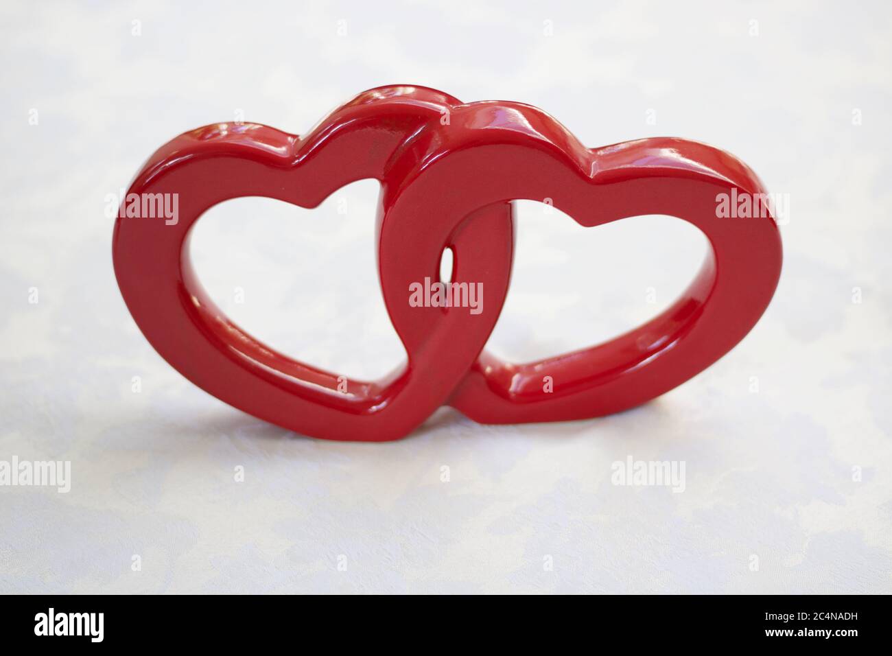 Two interconnected red ceramic hearts on white background with copyspace Stock Photo