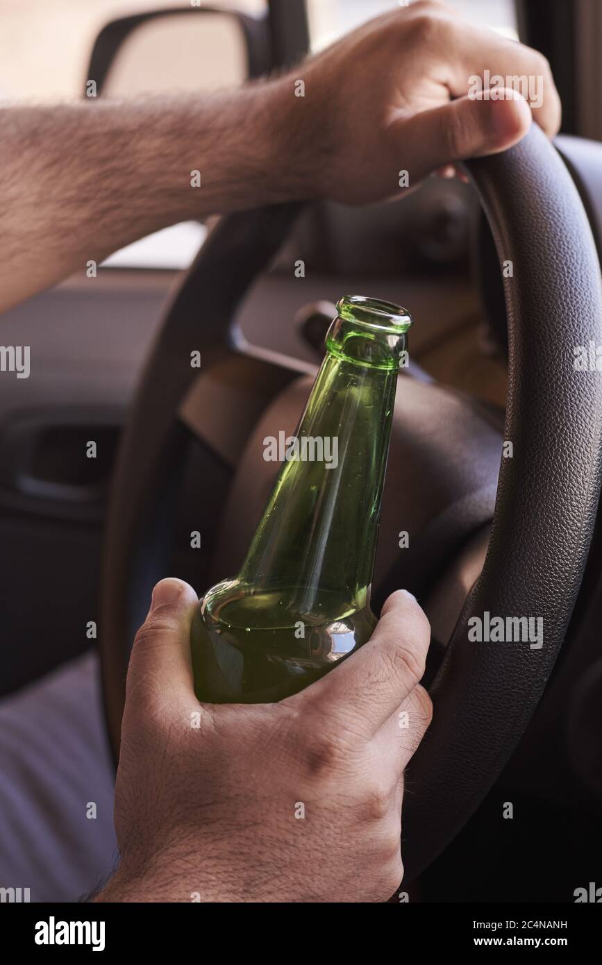 Bottle of beer in a man's hands driving the car during daytime Stock ...
