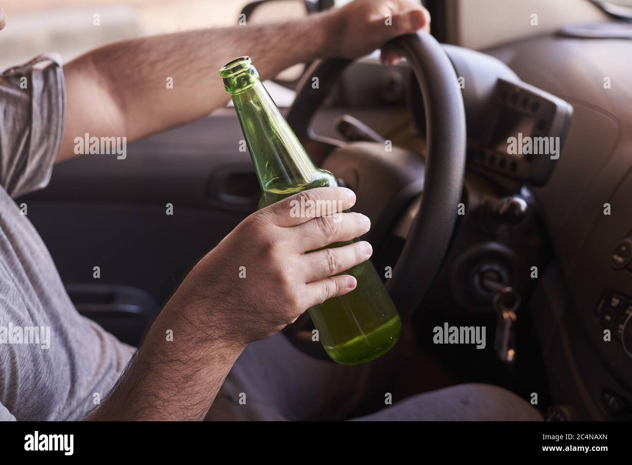 Bottle of beer in a man's hands driving the car during daytime Stock ...
